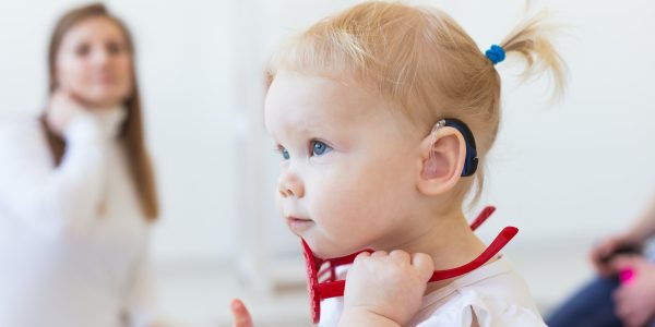 Baby girl wearing a hearing aid. Disabled child, disability and deafness concept Baby girl wearing a hearing aid. Disabled child, disability and deafness concept